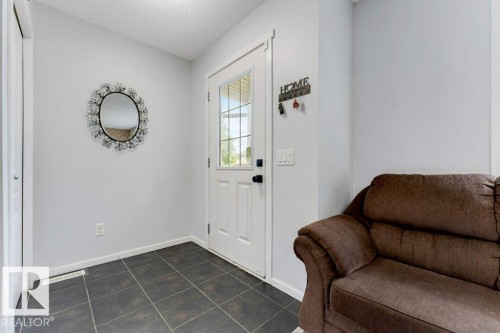Entryway featuring dark square tile flooring and a white paneled door with glass inserts - 3511 15A Street, Edmonton, AB 