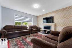 Living room featuring light wood-finish flooring, a contemporary fireplace with a white mantel, and a wall with a chevron pattern - 