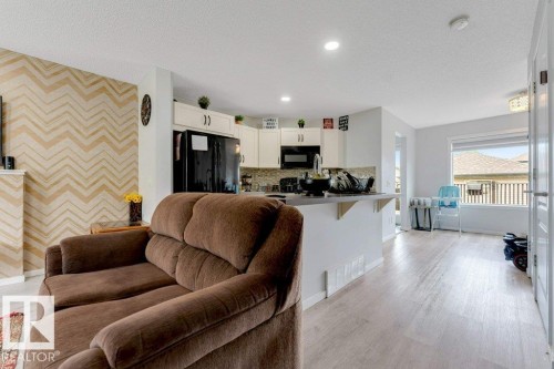 Open concept living space featuring a kitchen with white cabinetry and a breakfast bar - 3511 15A Street, Edmonton, AB 
