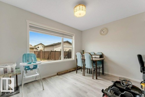 Naturally lit interior space featuring light wood-finish flooring, a contemporary semi-flush mount ceiling fixture, and a large picture window with white trim - 3511 15A Street, Edmonton, AB 