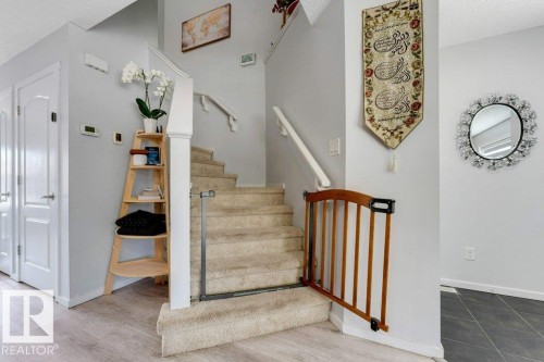 Carpeted staircase with white handrails and a wood-finish newel post - 3511 15A Street, Edmonton, AB 