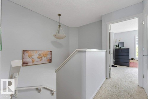 Upper landing featuring light gray walls, white trim, a semi-flush mount ceiling light, and plush light-colored carpeting - 3511 15A Street, Edmonton, AB 