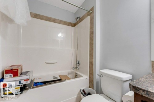 Bathroom featuring a white tub/shower combination, tiled shower surround, and a white toilet - 3511 15A Street, Edmonton, AB 