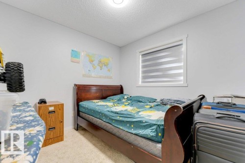 Carpeted room featuring light gray walls, a window with layered blinds, and a ceiling light fixture - 3511 15A Street, Edmonton, AB 