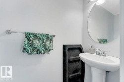 Pedestal sink with chrome faucet, complemented by a round wall-mounted mirror - 