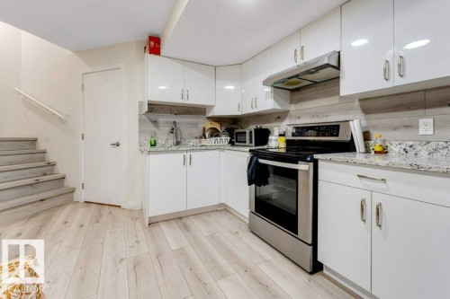 Kitchenette featuring white high-gloss cabinetry, speckled countertops, and a full suite of stainless steel appliances - 3511 15A Street, Edmonton, AB 