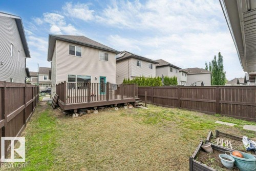 Expansive backyard featuring a large wood deck with railings, a turquoise exterior door, and full perimeter wood fencing - 3511 15A Street, Edmonton, AB 