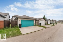 Detached rear garage featuring a vibrant teal overhead door, concrete driveway, and neutral siding - 