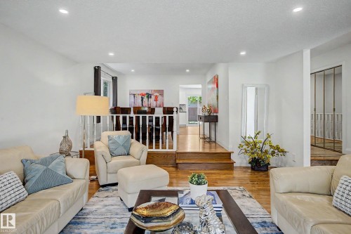 Spacious living area featuring wood-finish flooring, recessed lighting, and a white baluster railing - 3718 103B Street Nw, Edmonton, AB - Indoor Photo Showing Living Room