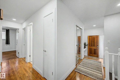 Hallway featuring wood-finish flooring, white paneled doors, recessed lighting, and a mirrored closet door - 3718 103B Street Nw, Edmonton, AB - Indoor Photo Showing Other Room