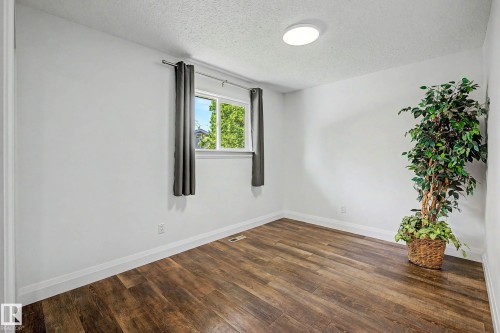 Room featuring wood-finish flooring, white baseboards, a single window, and a flush-mount ceiling light fixture - 3718 103B Street Nw, Edmonton, AB - Indoor Photo Showing Other Room