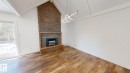 Vaulted ceilings with exposed beams and a contemporary light fixture complement the brick fireplace with hearth - 3718 103B Street, Edmonton, AB 