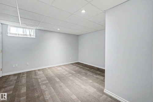Spacious room featuring light gray walls, recessed lighting, drop ceiling, and wood-finish flooring - 3718 103B Street Nw, Edmonton, AB - Indoor