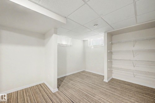 Spacious room featuring wood-finish flooring, white walls, and a drop ceiling with recessed lighting - 3718 103B Street Nw, Edmonton, AB - Indoor