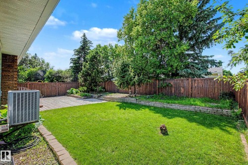 Private backyard featuring a wooden fence, a manicured lawn, a wooden deck, and mature trees - 3718 103B Street Nw, Edmonton, AB - Outdoor