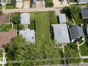 Expansive residential lot featuring a large grass area, mature trees, and concrete sidewalks - 10415 84 Street, Edmonton, AB 