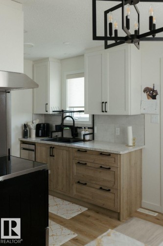 Modern kitchen featuring two-tone cabinetry with white upper cabinets and light wood-finish lower cabinets - 10503A 109 Street, Westlock, AB - Indoor Photo Showing Kitchen