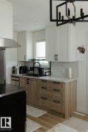 Modern kitchen featuring two-tone cabinetry with white upper cabinets and light wood-finish lower cabinets - 