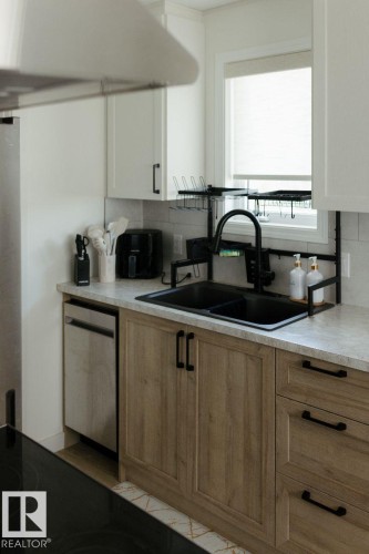 Modern kitchen featuring light wood-finish lower cabinetry and white upper cabinets - 10503A 109 Street, Westlock, AB - Indoor Photo Showing Kitchen With Double Sink