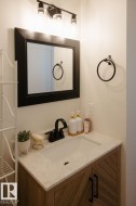 Bathroom vanity featuring a light-toned countertop with an integrated sink, matte black faucet, and a wood-finish cabinet with chevron-patterned doors - 