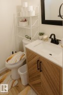 Bathroom vanity with wood-finish cabinetry featuring a herringbone pattern and matte black hardware - 