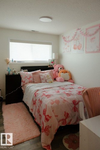 Bedroom featuring a large window with roller shades, a flush-mount ceiling light, and wood-finish flooring - 10503A 109 Street, Westlock, AB - Indoor Photo Showing Bedroom