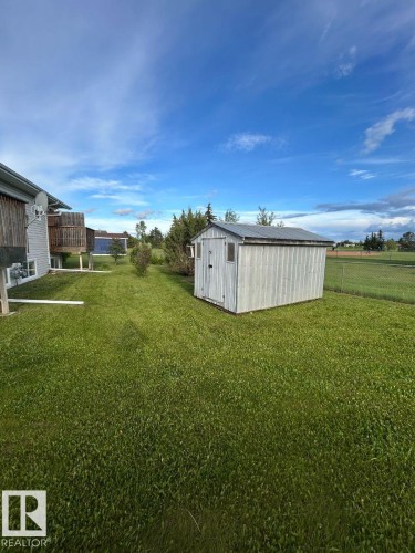 Expansive green lawn with a white storage shed featuring a corrugated metal roof and a small window - 10503A 109 Street, Westlock, AB - Outdoor