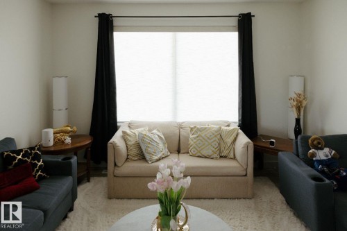 Bright living space featuring a large window with privacy blinds and dark curtain panels - 10503A 109 Street, Westlock, AB - Indoor Photo Showing Living Room