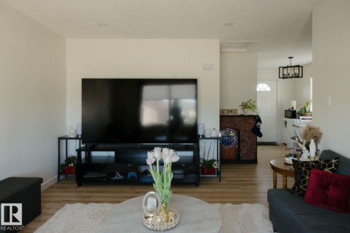 Living area featuring light wood-finish flooring, recessed lighting, and a white interior door with an arched glass insert - 10503A 109 Street, Westlock, AB - Indoor Photo Showing Living Room