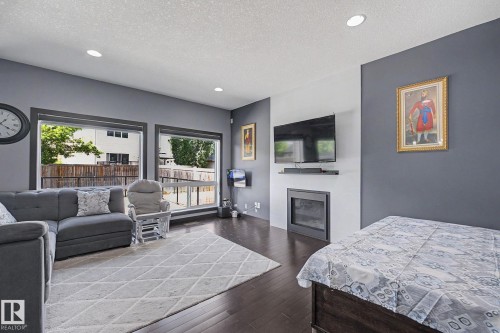 Living space featuring dark wood-finish flooring, recessed lighting, and large windows - 1944 68 Street, Edmonton, AB 