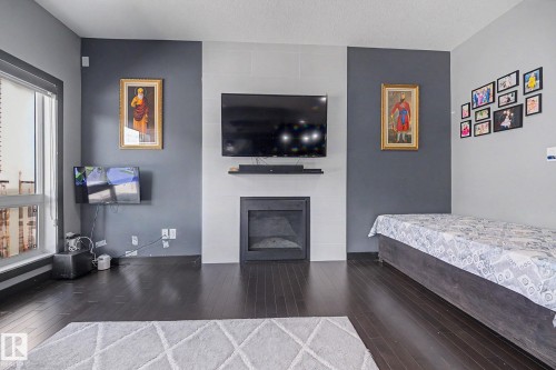 Dark wood-finish flooring complements the modern fireplace feature wall - 1944 68 Street, Edmonton, AB 