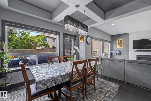 Open-concept living area featuring a coffered ceiling, wood-finish flooring, and a large picture window - 1944 68 Street, Edmonton, AB 