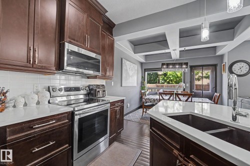 Modern kitchen featuring wood-finish cabinetry, stainless steel appliances, white countertops, and a subway tile backsplash - 1944 68 Street, Edmonton, AB 