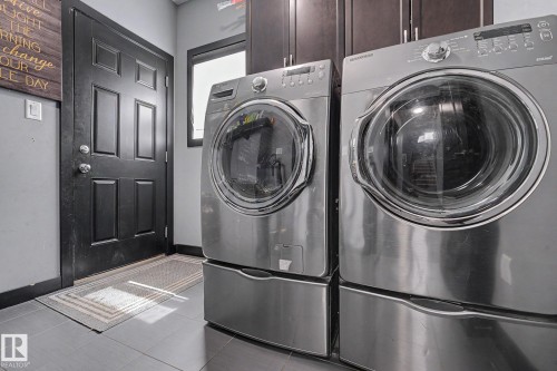 Front-loading washer and dryer set with stainless steel finish, mounted on pedestals - 1944 68 Street, Edmonton, AB 