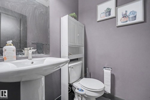Pedestal sink with chrome faucet, wall-mounted mirror, and white over-the-toilet storage cabinet - 1944 68 Street, Edmonton, AB 