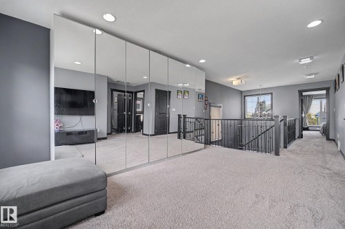 Open loft area featuring wall-to-wall mirrored closet doors, recessed ceiling lighting, and light-toned carpeting - 1944 68 Street, Edmonton, AB 