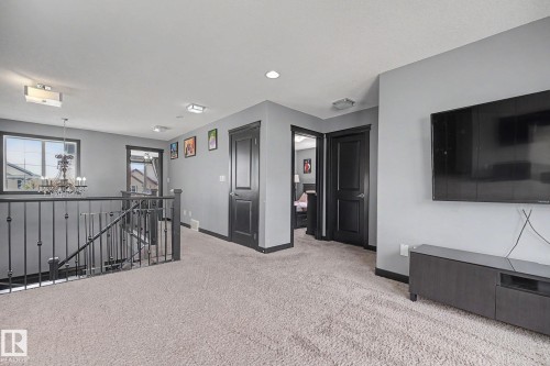 Spacious upper-level landing featuring light-colored carpeting, recessed lighting, and a contemporary chandelier - 1944 68 Street, Edmonton, AB 