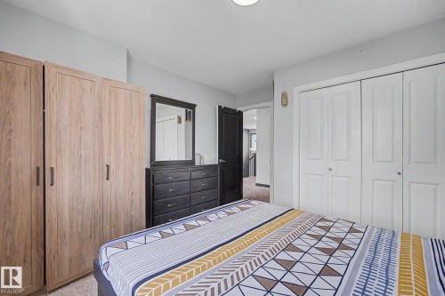 Bedroom featuring light wood-finish wardrobes, light gray walls, and white bi-fold closet doors - 1944 68 Street, Edmonton, AB 
