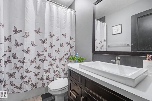 Modern bathroom featuring a rectangular vessel sink with chrome faucet, dark wood-finish vanity, and a large framed mirror - 1944 68 Street, Edmonton, AB 