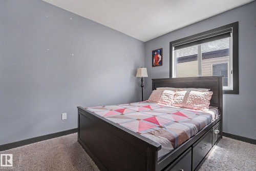 Carpeted room featuring a window with dark trim and roller shade, and light blue walls with dark baseboards - 1944 68 Street, Edmonton, AB 