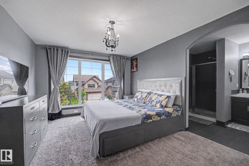 Spacious room featuring a large picture window, gray walls, and plush carpet flooring - 1944 68 Street, Edmonton, AB 