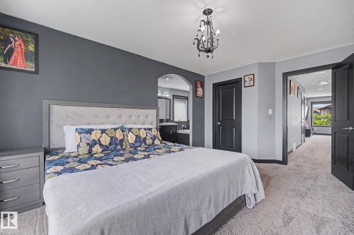 Carpeted room with a dark accent wall, featuring a chandelier light fixture - 1944 68 Street, Edmonton, AB 