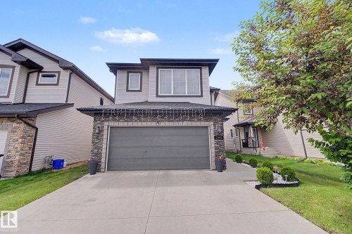 Two-story residential exterior featuring light-colored siding and dark trim accents - 1944 68 Street, Edmonton, AB 