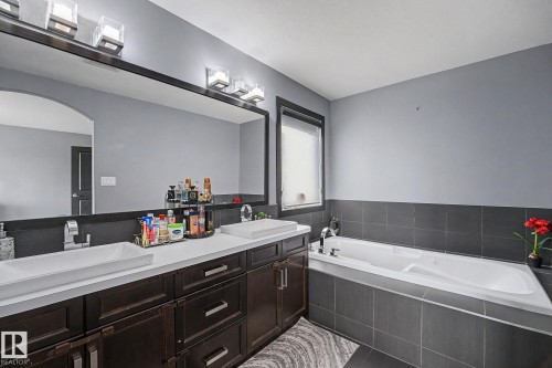 Bathroom featuring a double vanity with rectangular vessel sinks, dark wood cabinetry, and a full-width mirror - 1944 68 Street, Edmonton, AB 