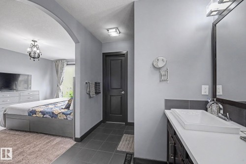 Bathroom vanity featuring a rectangular vessel sink, white countertop, dark wood-finish cabinetry, and a framed mirror - 1944 68 Street, Edmonton, AB 