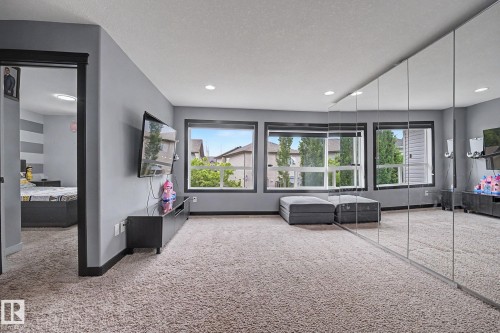 Spacious room featuring wall-to-wall carpeting, multiple windows, recessed ceiling lighting, and a full wall of mirrored panels - 1944 68 Street, Edmonton, AB 