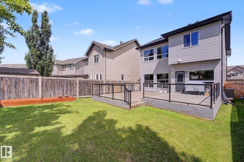 Expansive backyard featuring a multi-level deck with glass panel railings, a manicured lawn, and a privacy fence - 1944 68 Street, Edmonton, AB 