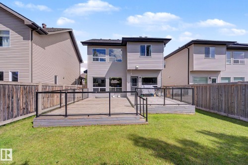 Spacious backyard featuring a multi-level wood deck with contemporary glass and black metal railings - 1944 68 Street, Edmonton, AB 