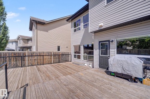 Expansive wood-finish deck with black frame glass railing, offering substantial outdoor living space - 1944 68 Street, Edmonton, AB 