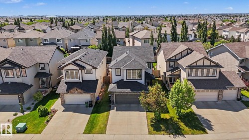 Contemporary suburban residence featuring a black shingle roof, stone and stucco exterior, an attached garage, a paved driveway, and established front landscaping - 1944 68 Street, Edmonton, AB 